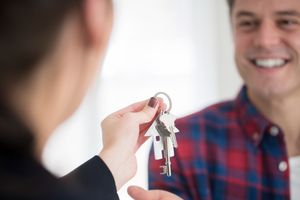 A close-up of a person’s hand passing a set of keys to another, symbolizing trust, empowerment, and the act of relinquishing control to enable team autonomy and true business agility.