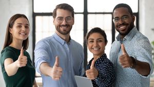 A group of people smiling with thumbs up